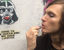 Evan Greer ’07 applies lipstick in front of a mural